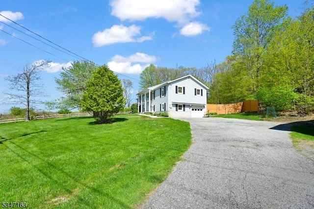 view of front of home featuring fence, an attached garage, driveway, and a front yard