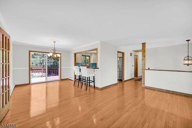 living area featuring wood finished floors, baseboards, a baseboard heating unit, and a chandelier