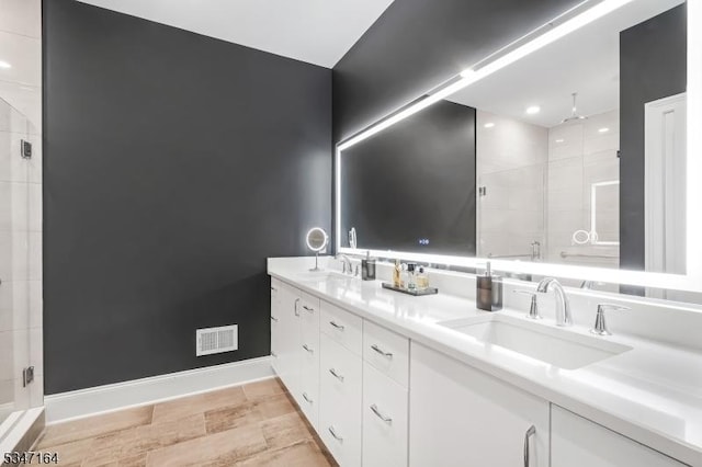 full bathroom featuring a shower stall, baseboards, and double vanity
