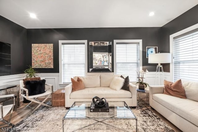 living room featuring wood finished floors, a decorative wall, a wainscoted wall, and recessed lighting