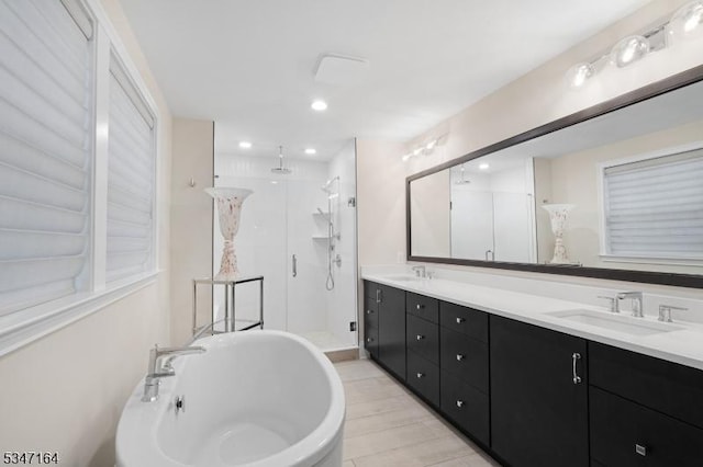 bathroom with a stall shower, a soaking tub, double vanity, wood finished floors, and recessed lighting