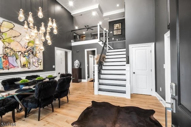 entryway featuring a high ceiling, stairs, wood finished floors, crown molding, and baseboards