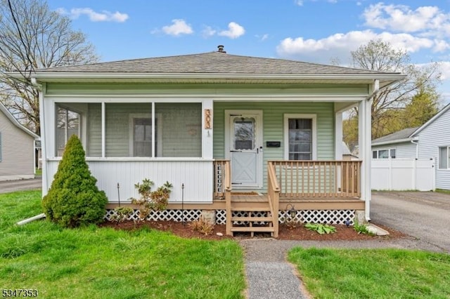 bungalow-style house with roof with shingles and a front lawn