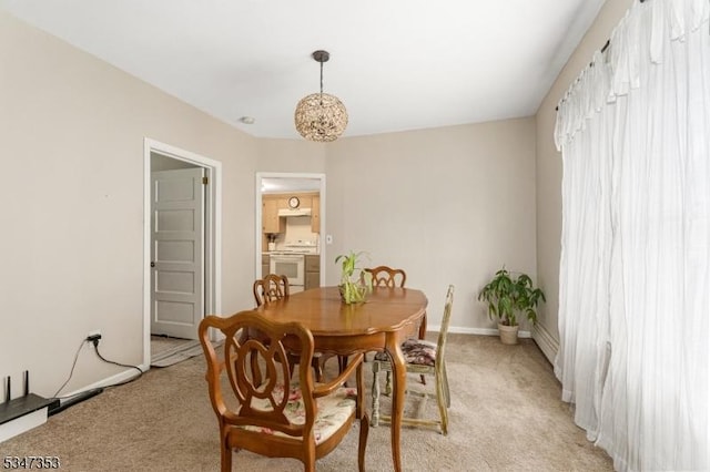 dining space with baseboards, an inviting chandelier, and light colored carpet