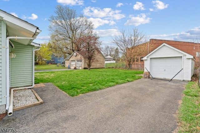 view of yard featuring an outdoor structure, aphalt driveway, and a garage