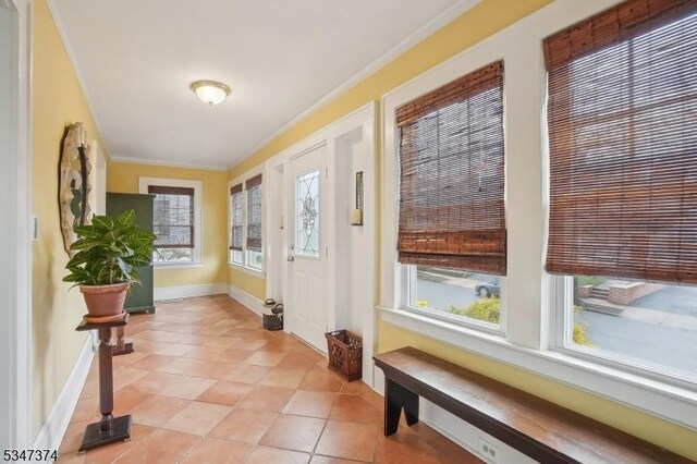 foyer entrance featuring baseboards, ornamental molding, and light tile patterned floors