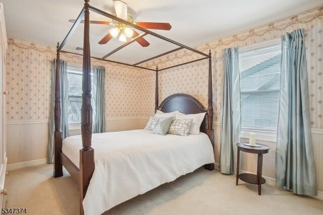 carpeted bedroom with visible vents, wallpapered walls, and a ceiling fan