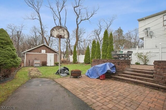 view of patio / terrace with an outbuilding, a fire pit, and fence