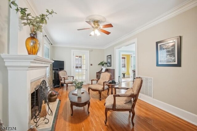 sitting room with light wood finished floors, ornamental molding, ceiling fan, and visible vents