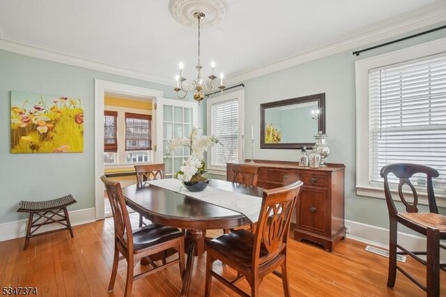 dining space with light wood finished floors, baseboards, crown molding, and a chandelier