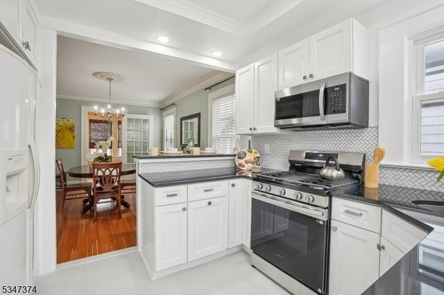 kitchen featuring ornamental molding, dark countertops, a peninsula, and stainless steel appliances