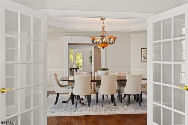 dining room with crown molding, an inviting chandelier, and dark wood-style floors