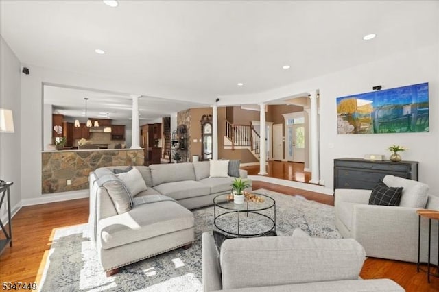 living room with recessed lighting, decorative columns, stairs, and wood finished floors