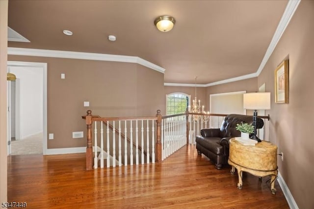 corridor featuring crown molding, a notable chandelier, wood finished floors, and an upstairs landing