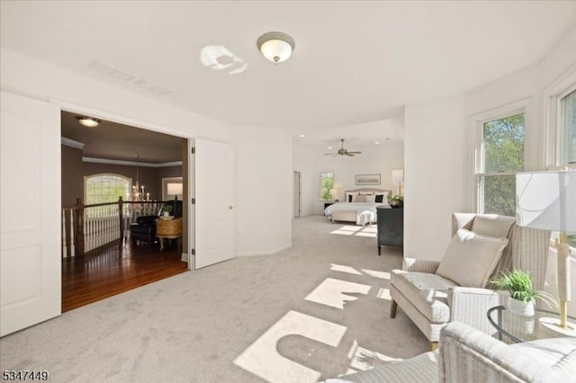 living room featuring a healthy amount of sunlight, carpet, and ceiling fan with notable chandelier