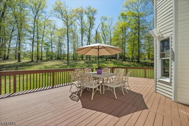wooden deck with a lawn and outdoor dining space