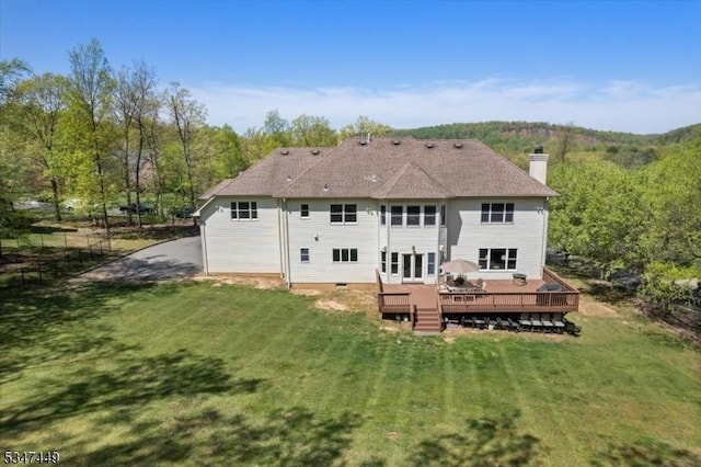 back of property with a lawn, a wooden deck, and a chimney