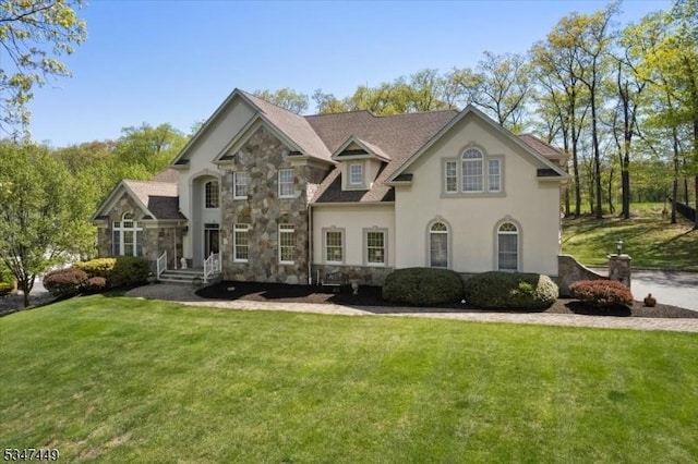 view of front facade featuring stucco siding, stone siding, and a front yard