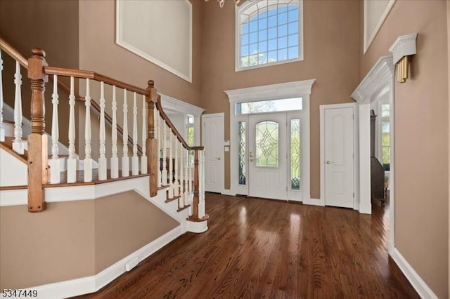 foyer entrance featuring stairway, baseboards, wood finished floors, and a towering ceiling