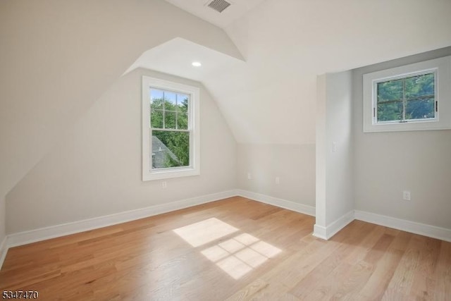 additional living space featuring baseboards, visible vents, light wood finished floors, and lofted ceiling