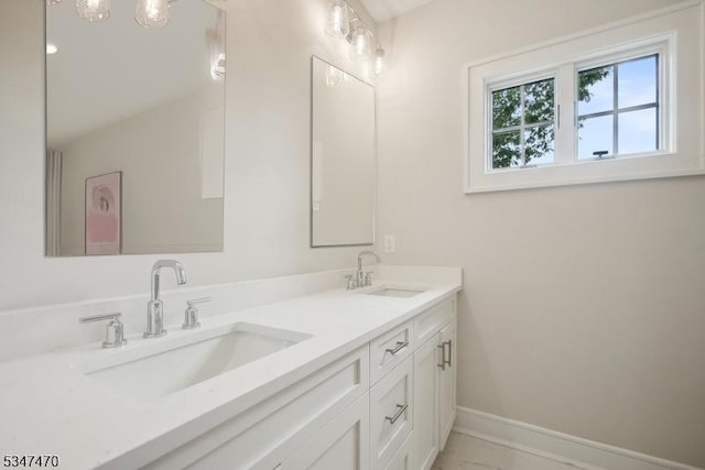 bathroom with double vanity, a sink, and baseboards