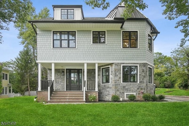 view of front facade featuring covered porch, a front lawn, and stone siding