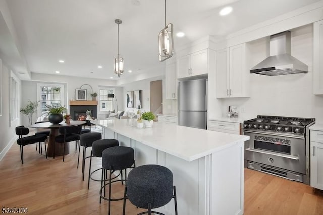 kitchen with recessed lighting, stainless steel appliances, wall chimney exhaust hood, and a kitchen island