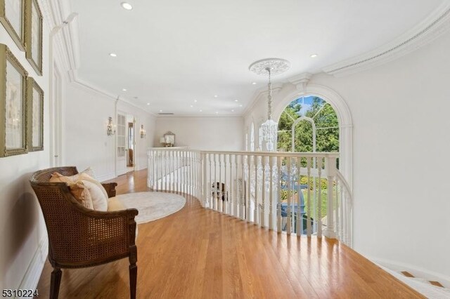 hallway featuring an inviting chandelier, recessed lighting, ornamental molding, and wood finished floors
