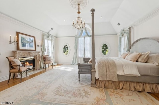 bedroom with visible vents, baseboards, a chandelier, wood finished floors, and a premium fireplace
