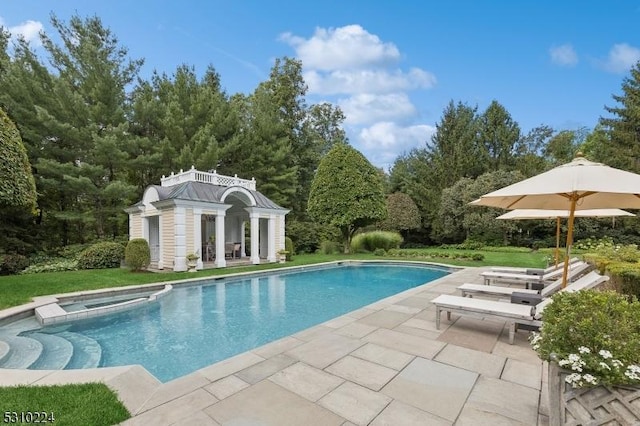 view of swimming pool with a patio, a pool with connected hot tub, a storage structure, and an outdoor structure