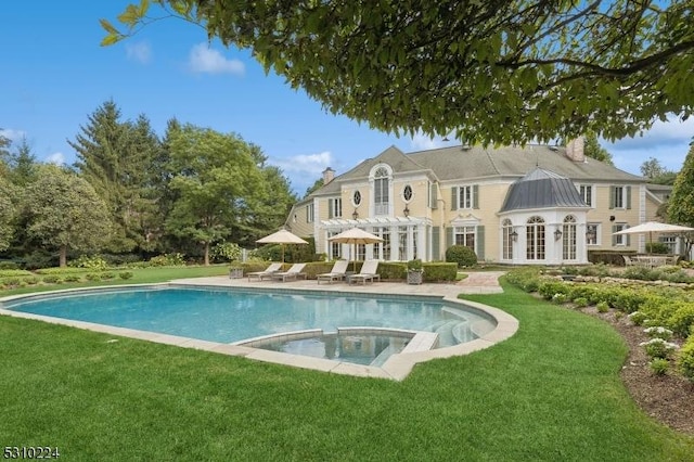outdoor pool featuring a patio area, french doors, an in ground hot tub, and a lawn
