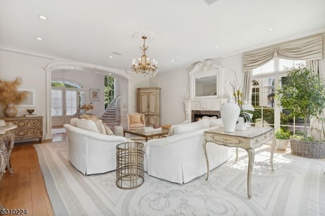 living area with arched walkways, wood-type flooring, recessed lighting, a lit fireplace, and french doors