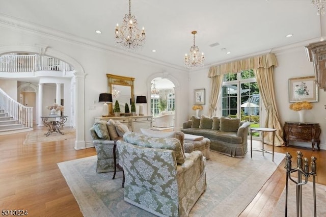 living area featuring arched walkways, a notable chandelier, light wood-type flooring, and ornamental molding