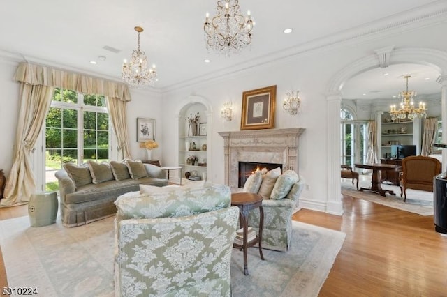 living room with crown molding, an inviting chandelier, arched walkways, a high end fireplace, and built in shelves