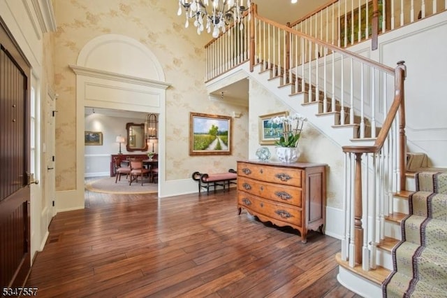 entryway featuring wood-type flooring, stairway, a towering ceiling, and a notable chandelier