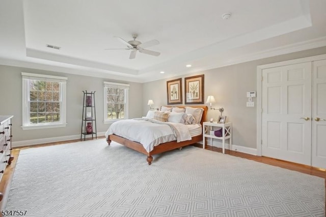 bedroom featuring light wood finished floors, baseboards, visible vents, recessed lighting, and a raised ceiling