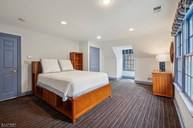 bedroom with baseboards, dark colored carpet, multiple windows, and visible vents