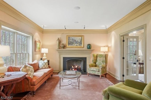 living area with ornamental molding, a wealth of natural light, a warm lit fireplace, and wood finished floors
