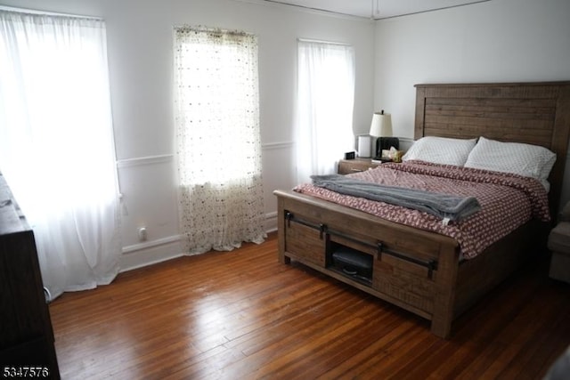 bedroom featuring baseboards, wood finished floors, and crown molding