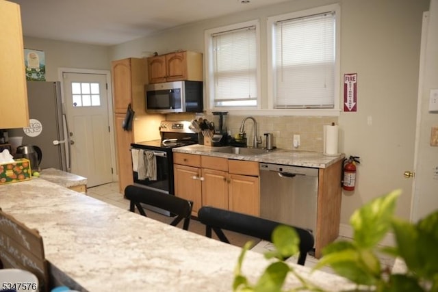 kitchen with decorative backsplash, light countertops, a sink, and appliances with stainless steel finishes