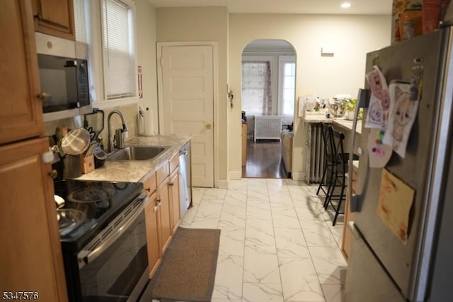kitchen with a sink, marble finish floor, arched walkways, a healthy amount of sunlight, and appliances with stainless steel finishes