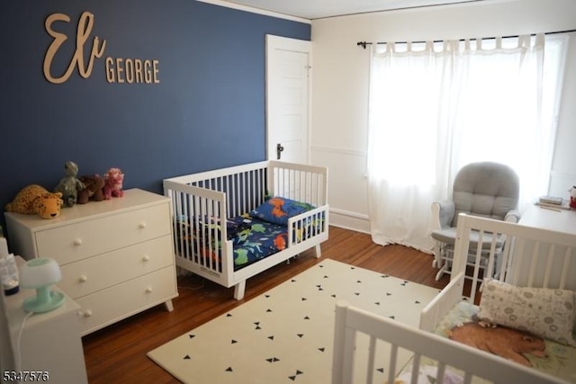 bedroom with wood finished floors and a crib