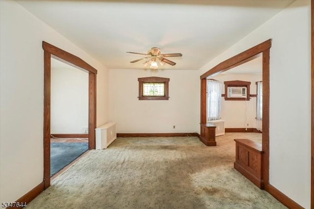 unfurnished room featuring carpet, baseboards, ceiling fan, and radiator