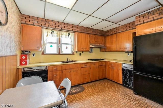 kitchen with black appliances, light countertops, a paneled ceiling, a sink, and light flooring