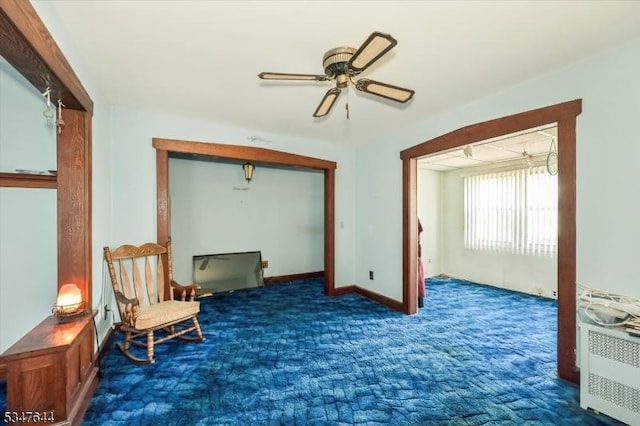 living area featuring carpet, ceiling fan, and baseboards