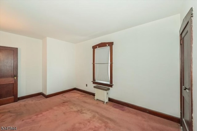 carpeted empty room with radiator heating unit and baseboards