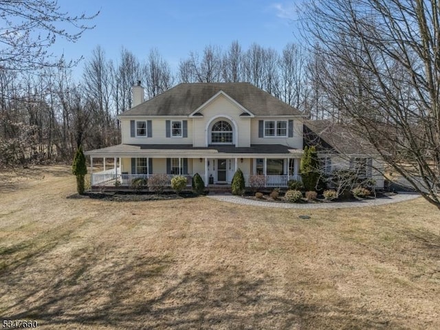view of front of home featuring a front yard, a porch, and a chimney
