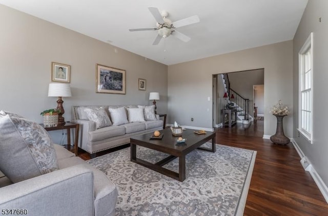 living room with baseboards, wood finished floors, stairs, and ceiling fan
