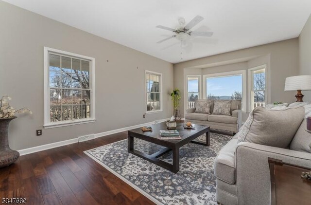 living room with visible vents, baseboards, a ceiling fan, and wood finished floors