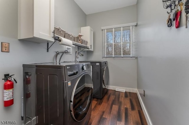 laundry area with washing machine and clothes dryer, dark wood-style floors, baseboards, visible vents, and cabinet space